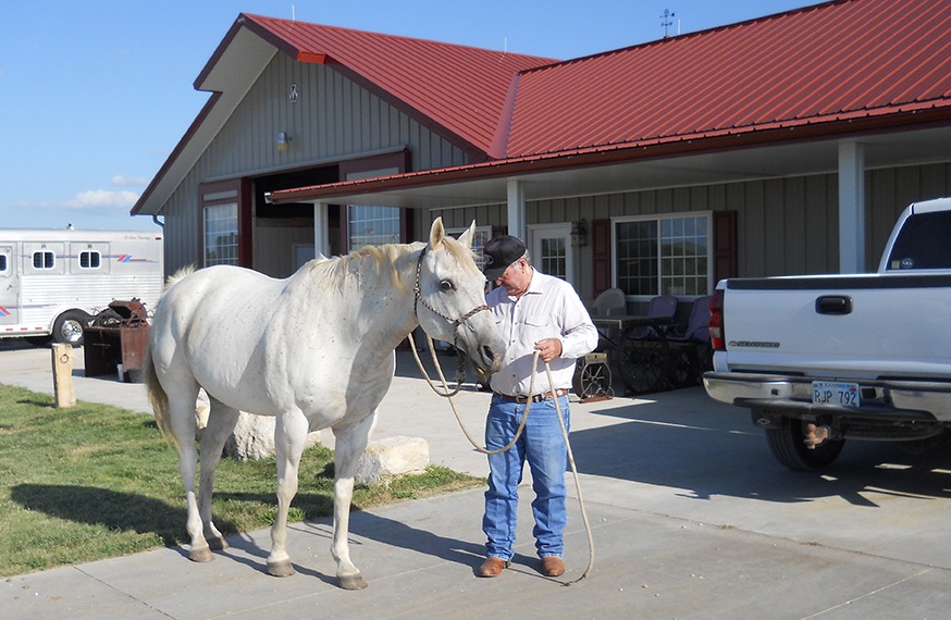 Renowned livestock nutritionist Dr. Phil Phar is with his horse, Flint, in front of the home-barn headquarters just north of Council Grove.