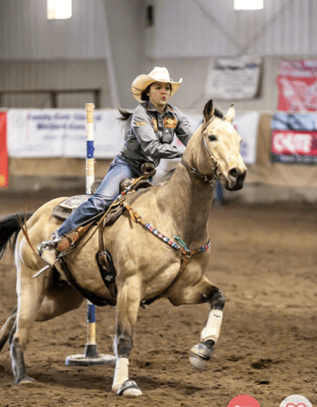 Jayme Flowers of Garden City shows her winning rodeo abilities in pole bending on her buckskin gelding called Jay. 